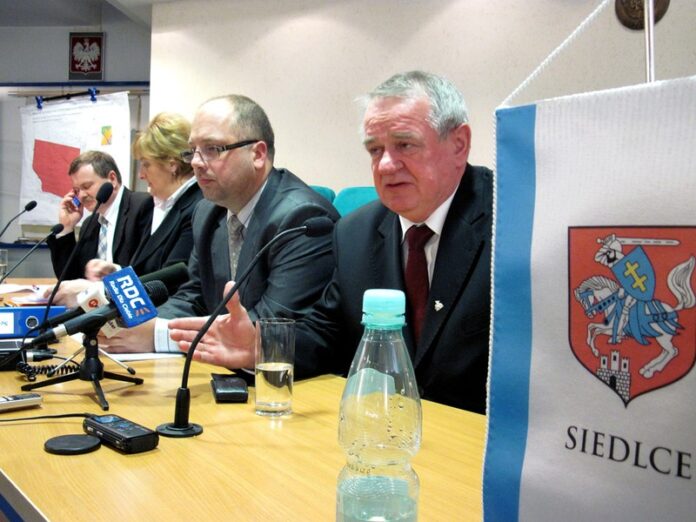 Ludzie elegancko ubrani siedzą przy stole z mikrofonami