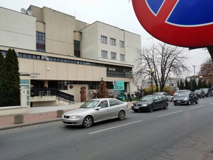 Budynek ze stojącymi samochodami i znakiem drogowym na pierwszym planie