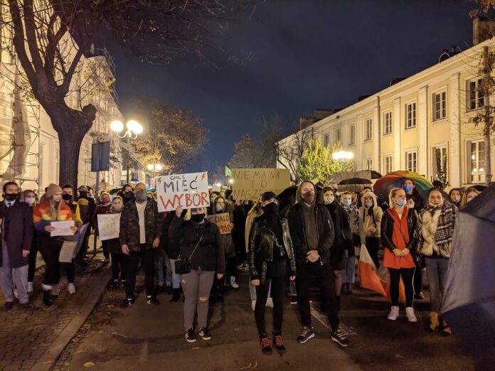 Nocny protest na ulicy miasta, uczestnicy trzymają transparent z napisem Chcę mieć wybór