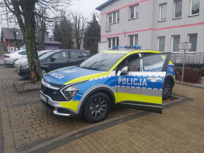 Policyjny samochód stoi na parkingu przed budynkiem.