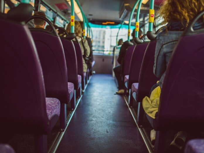 Wnętrze autobusu widziane z ostatnich siedzeń, w przytłumionych kolorach z zabarwieniem fioletu i żółci.