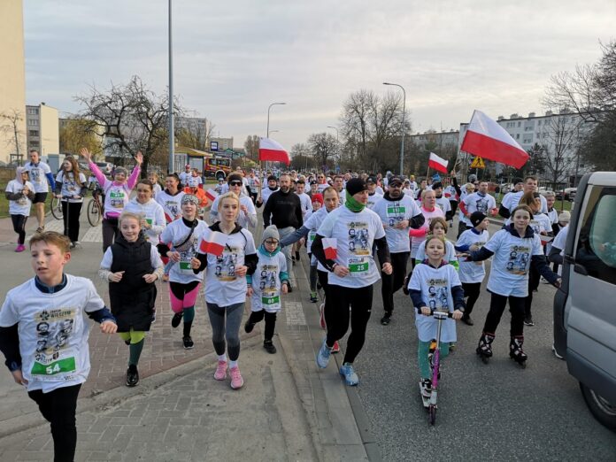 Grupa ludzi biegnąca w wyścigu, zdeterminowane twarze i dynamiczne ruchy, ukazujące ducha rywalizacji.