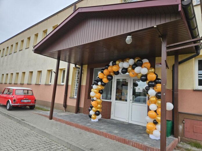 Wejście do budynku otoczone białymi, żółtymi i czarnymi balonami.