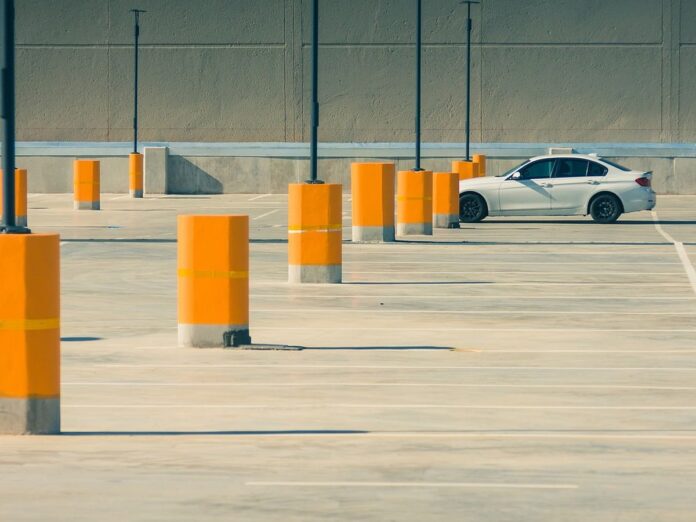Parkingi z dużą ilością miejsc postojowych i samochodem w tle.