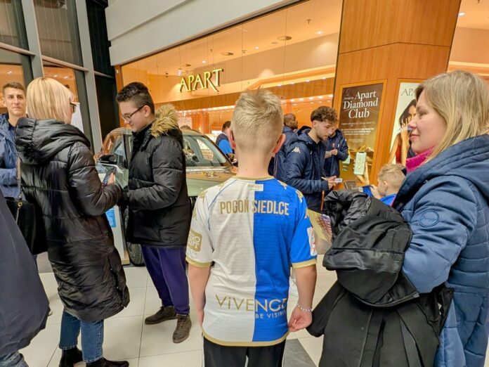 Grupa osób w tym jedna z koszulką sportową z napisem 