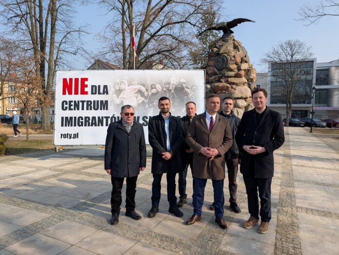 Grupa mężczyzn przed billboardem z hasłem 