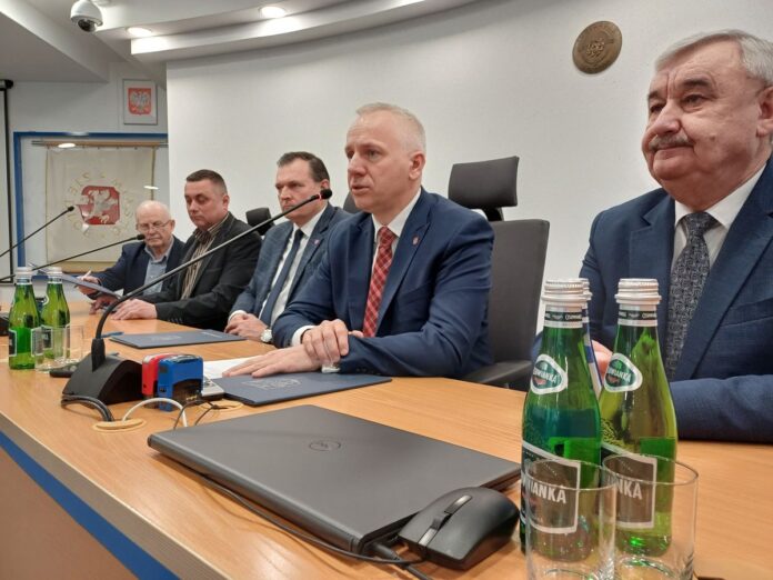 Grupa mężczyzn siedzących przy stole, rozmawiających i używających mikrofonów do dyskusji.