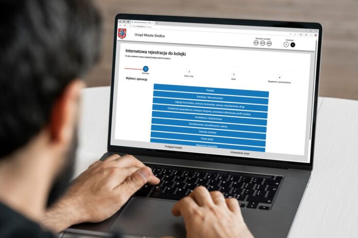 Mężczyzna korzysta z laptopa, na którym wyświetla się strona internetowa.
