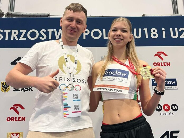 Sportowczyni cieszy się ze zdobytego złotego medalu prezentując go w dłoni i obejmuje mężczyznę.