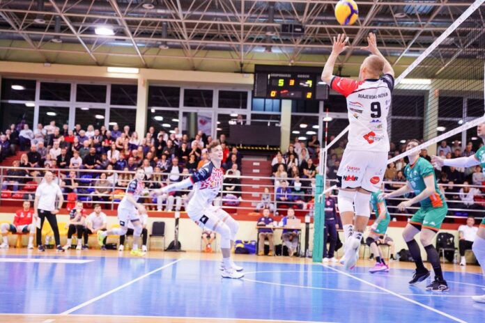 Zawodnicy siatkówki w akcji podczas meczu, dynamiczne ruchy i intensywna rywalizacja na boisku.