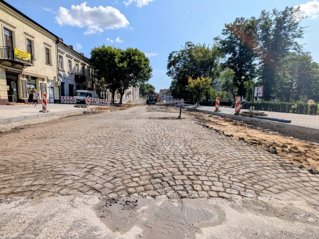 Ulica w mieście ze zdjętym asfaltem i odsłoniętą starą kostką brukową. 