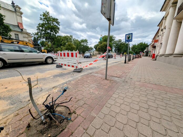 Remont ulicy w mieście, w tle duży budynek i samochody.
