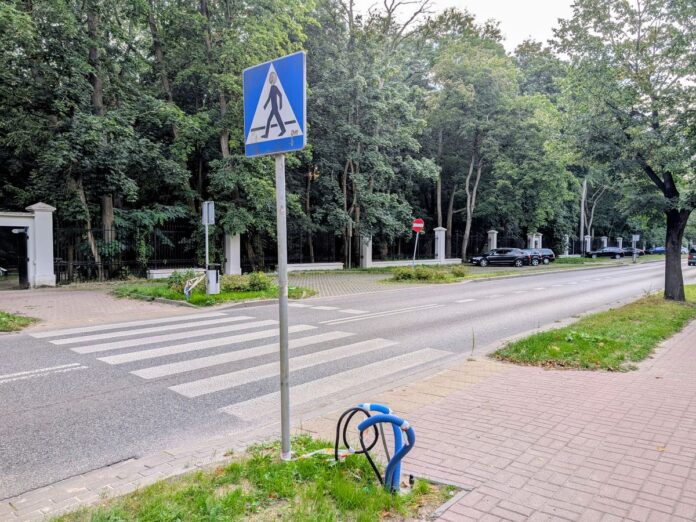 Ulica z przejściem dla pieszym w tle drzewa.