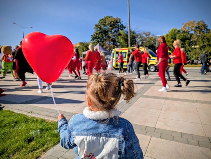 . Mała dziewczynka trzyma balon w kształcie serca, uśmiechając się radośnie.