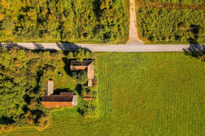 Widok z lotu ptaka na farmę i drogę otoczoną zielonymi polami.