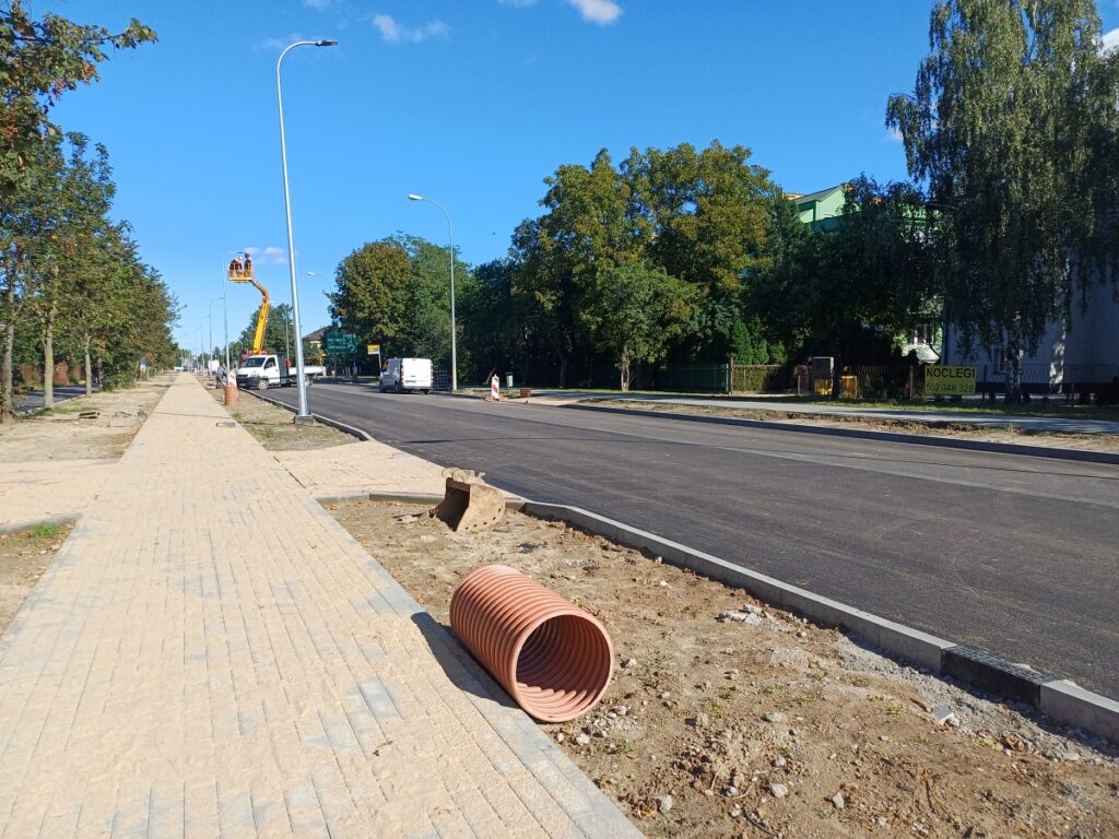 Remont ulicy w mieście, widać wyłożony nowy asfalt i niedokończoną ścieżkę rowerową. 