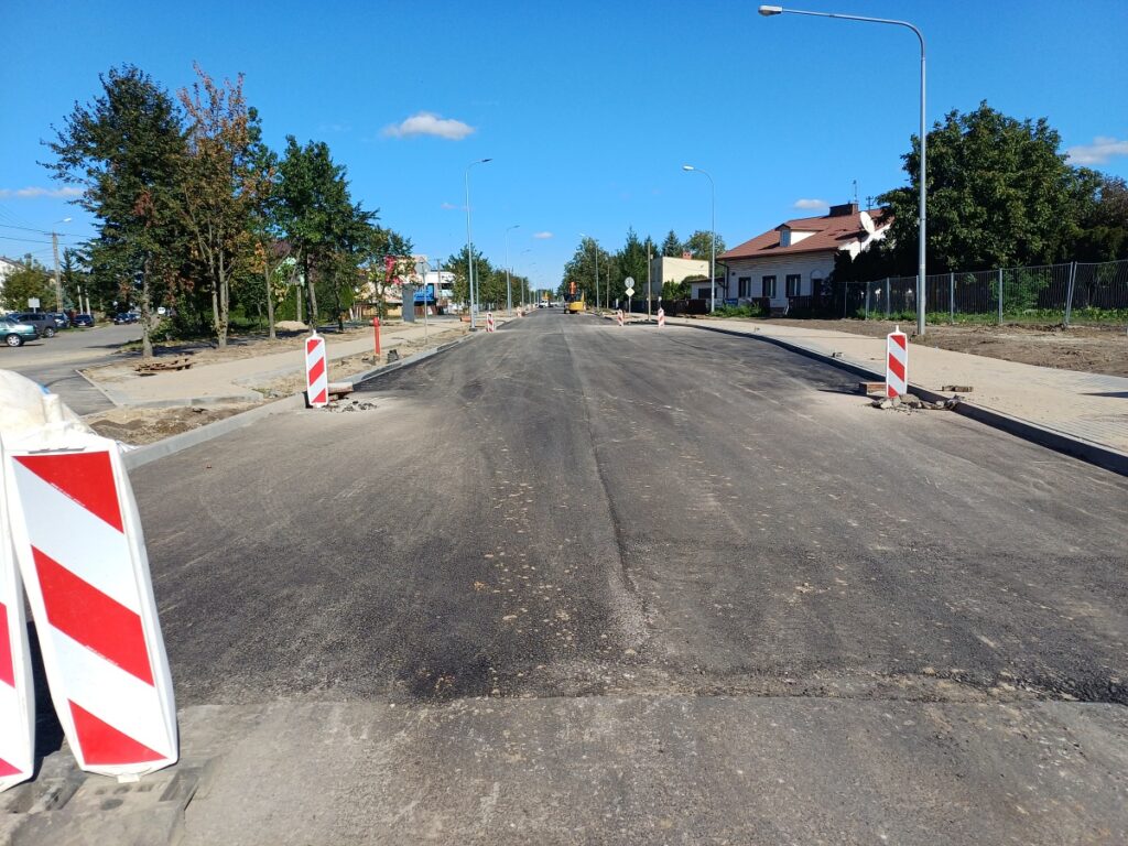 Ulica w mieście w budowie. Widać nowo położony asfalt. 