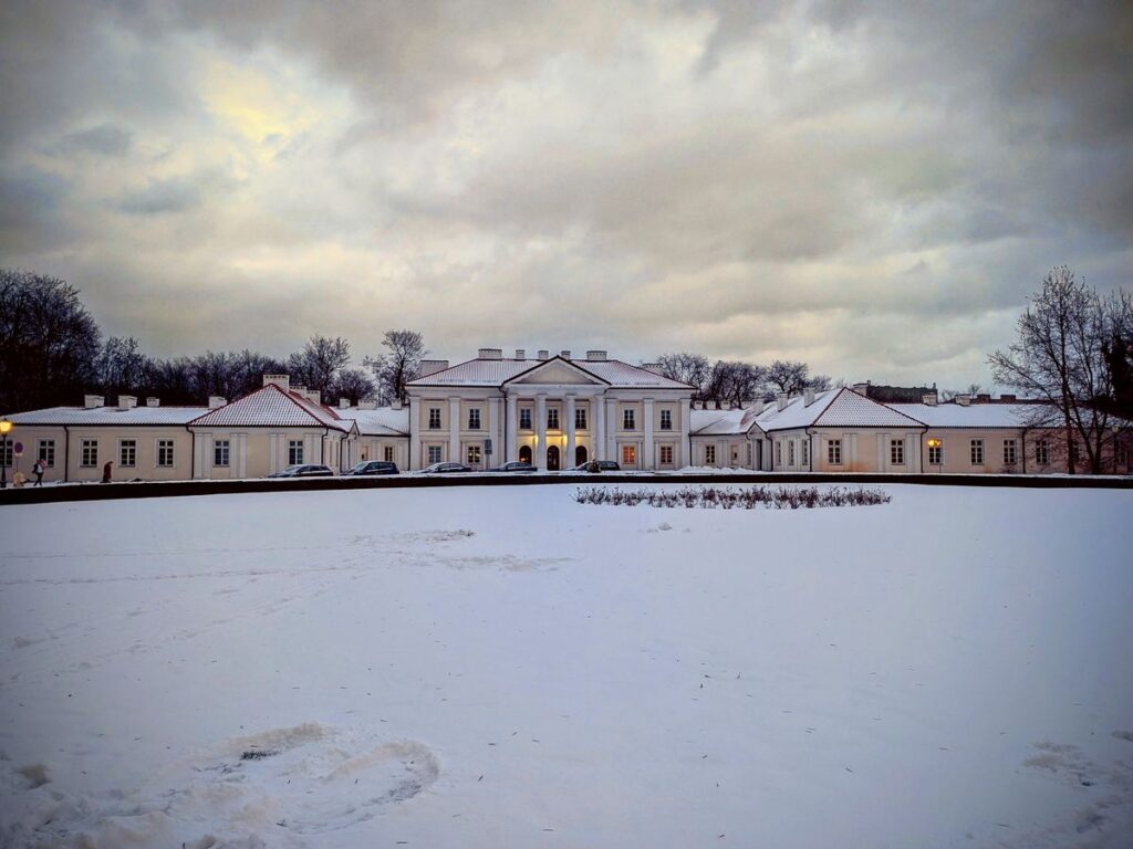 Duży zabytkowy jasny budynek z kolumnami w zimowej scenerii