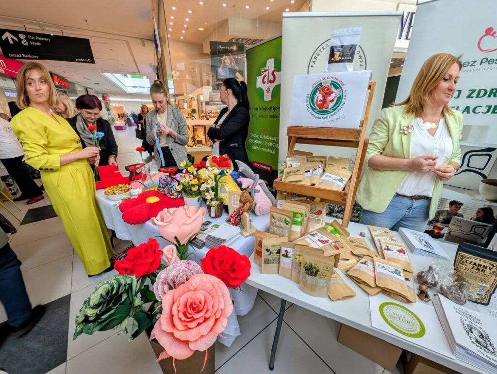 Kobieta przy stole z różnorodnymi przedmiotami obok niej.