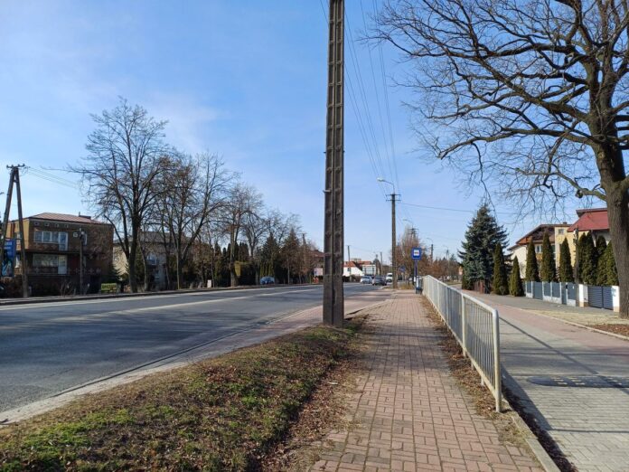 Ulica w mieście z chodnikiem i oświetleniem ulicznym w okresie jesiennym.