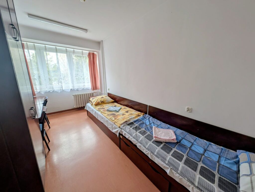 Pokój z dwoma łóżkami i biurkiem, stworzony do wypoczynku i pracy.