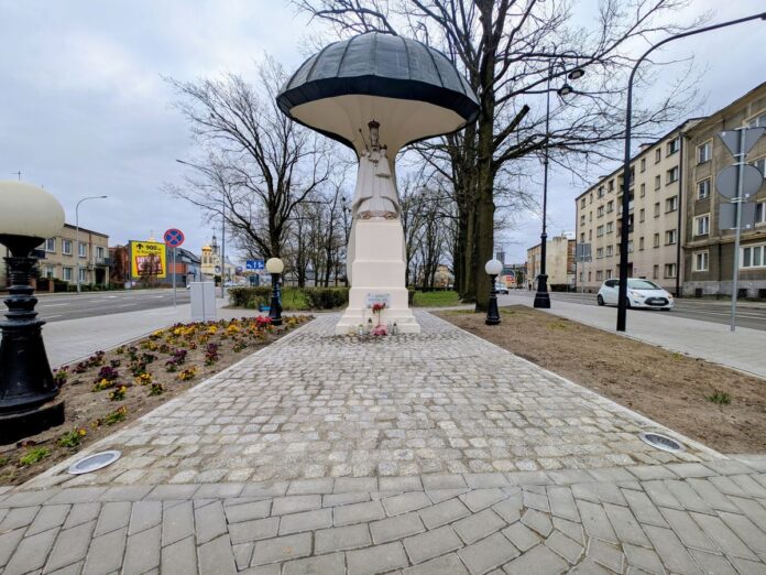 Pomnik z Figurą Matki Boskiej stojący na granitowej kostce.