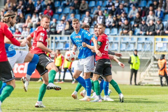 Kilku piłkarzy gra na boisku, intensywnie rywalizując o piłkę.