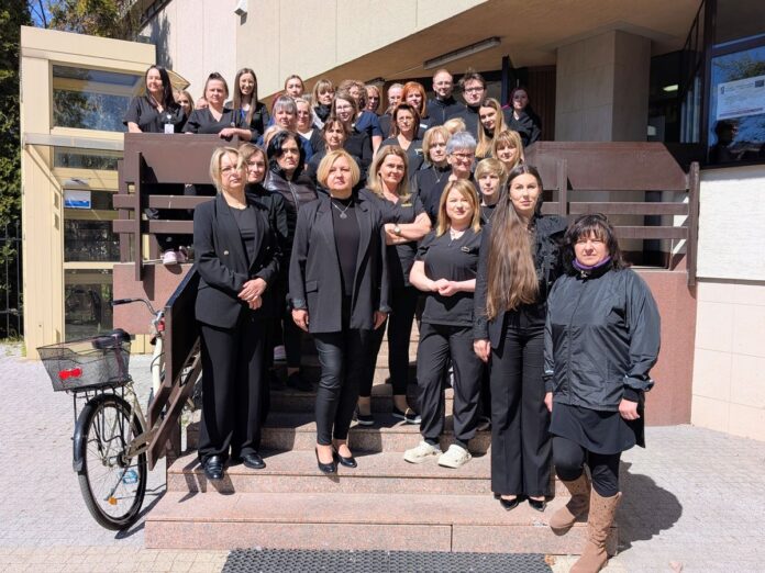 Grupa około 20 kobiet ubrana na czarno stoi przed budynkiem.