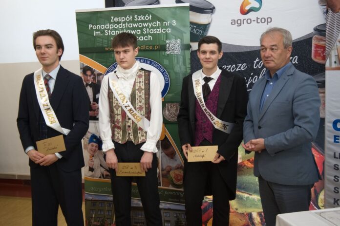 Trzech mężczyzn w garniturach stoi obok banera.