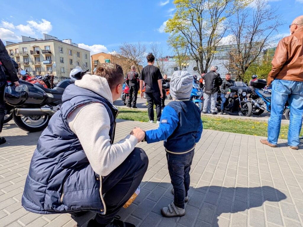Mężczyzna z synem obserwują zlot motocyklowy 