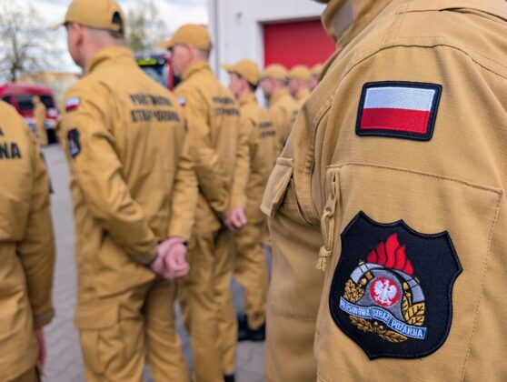 Grupa ludzi w mundurach strażackich z flagą na ramieniu
