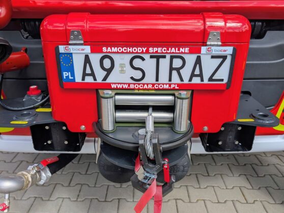 Strażacki w&oacute;z w kolorach czerwonym i białym, zaparkowany na drodze.