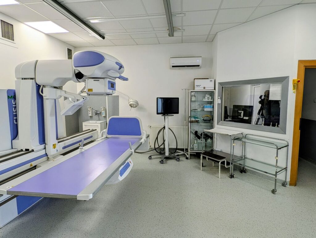 Medyczny pokój z stołem, krzesłem i różnym sprzętem medycznym.