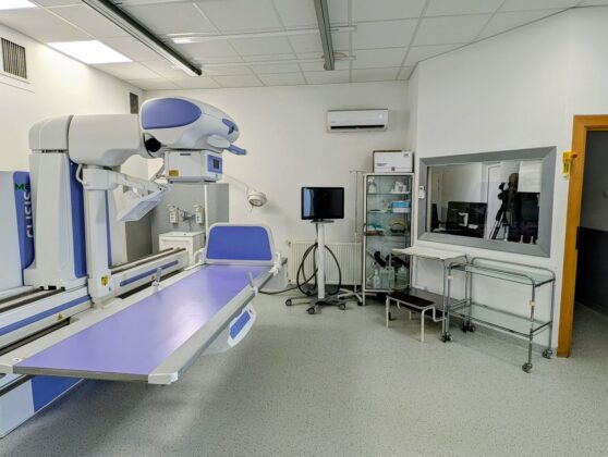 Medyczny pok&oacute;j z stołem, krzesłem i r&oacute;żnym sprzętem medycznym.