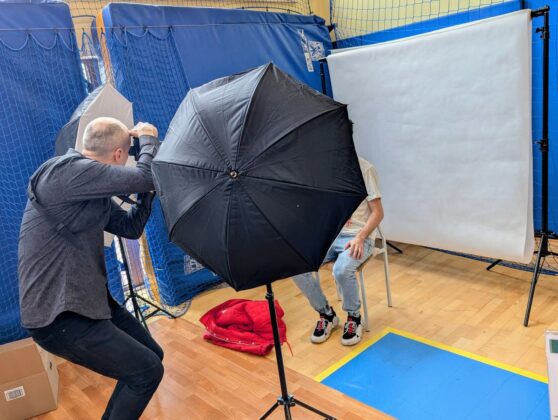 Mężczyzna robi zdjęcie innego mężczyzny w studiu fotograficznym.