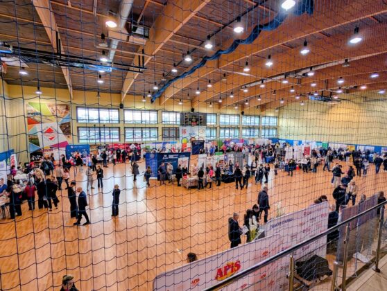 Wnętrze dużej siłowni z osobami poruszającymi się w r&oacute;żnych kierunkach.