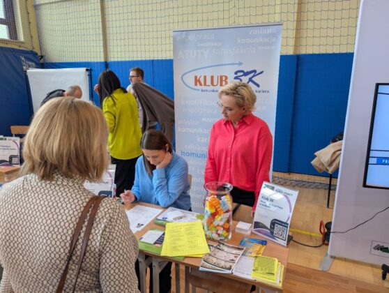 Ludzie przy stole z dokumentami i znakiem, omawiający ważne zagadnienia.