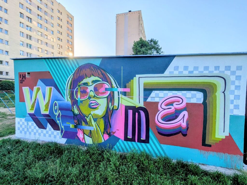 Kolorowy mural z geometrycznymi kształtami i kobiecą twarzą.
