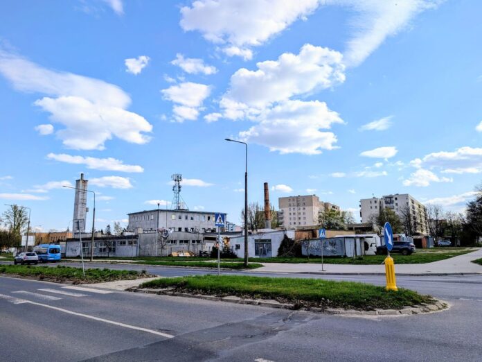 Widok na stare niewysokie budynki poprzemysłowe stojące przy ulicy.