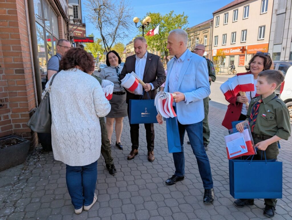 Grupa ludzi stoi wokół mężczyzny trzymającego torbę.