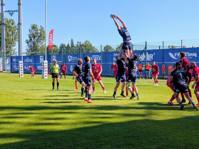 Mecz rugby: zawodnicy podnoszą kolegę z drużyny podczas wrzutu z autu, aby złapał piłkę