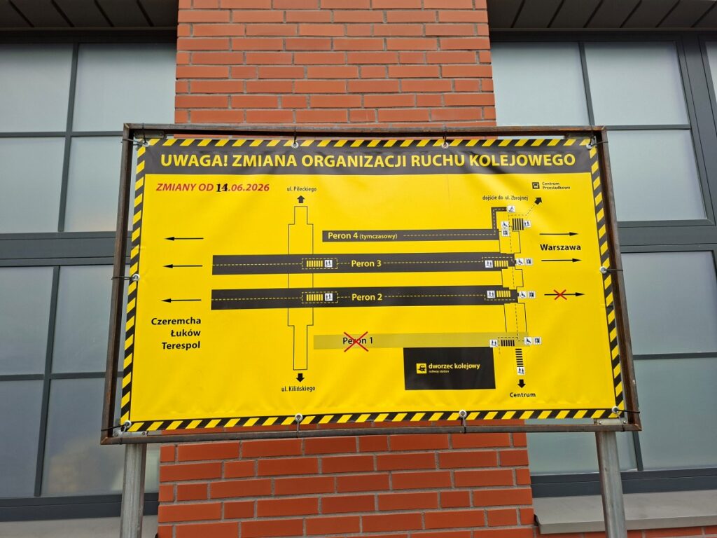 Żółto-czarny znak umieszczony na budynku, informujący o ważnych informacjach lub ostrzeżeniach.