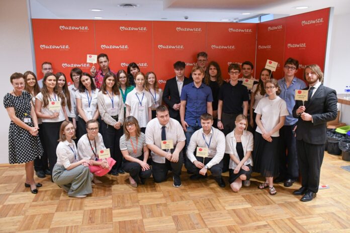 grupa ludzi z tabliczkami pozuje do zdjęcia uśmiechając się
