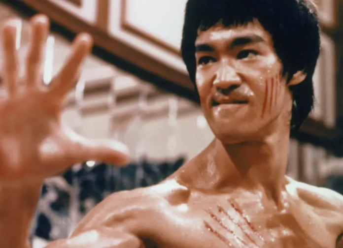 Bruce Lee z krwawymi zadrapaniami na twarzy i klatce piersiowej, w skupieniu podczas walki