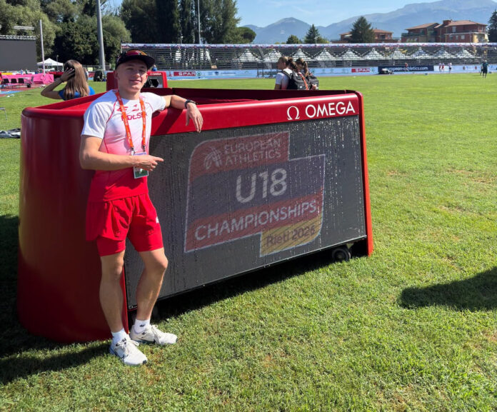 Polski lekkoatleta pozuje przy tablicy informacyjnej European Athletics U18 Championships Rieti 2026