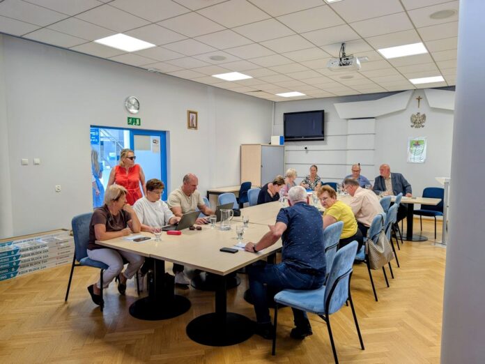 Grupa osób siedząca przy stole w sali konferencyjnej podczas spotkania