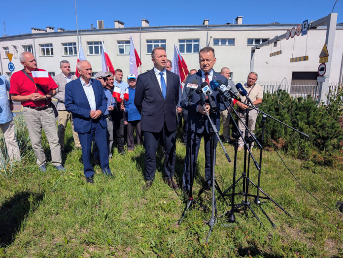 Mariusz Błaszczak i Przemysław Czarnek podczas konferencji prasowej na tle budynku i polskich flag