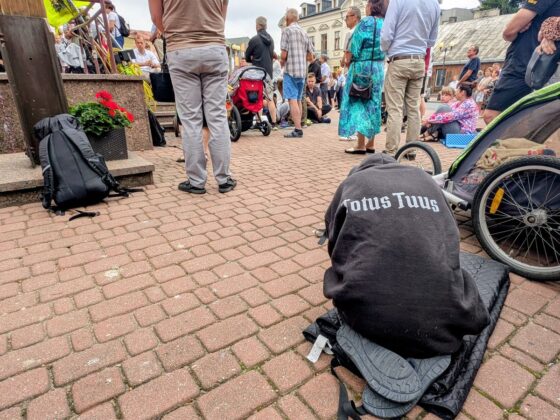 Osoba siedząca tyłem w czarnej bluzie z napisem Totus Tuus na tle zgromadzonego tłumu