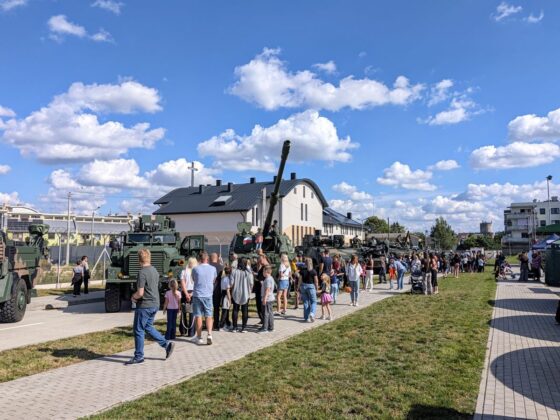 Tłum zwiedzających oglądający sprzęt wojskowy i pojazdy opancerzone na pikniku militarnym